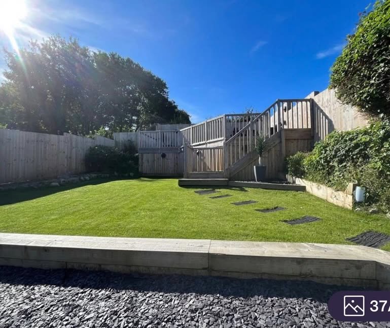 Landscaped rear garden with lawn and raised deck