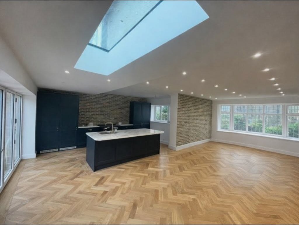 Open plan kitchen with herringbone floor and skylight